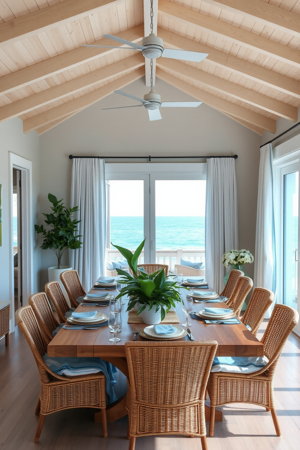 A coastal dining room featuring a large wooden table surrounded by white wicker chairs. The table is adorned with various seashell centerpieces in different shapes and sizes, complemented by soft blue table linens. The walls are painted in a light sandy beige, evoking a beachy feel. Large windows with sheer white curtains allow natural light to flood the space, enhancing the coastal charm.