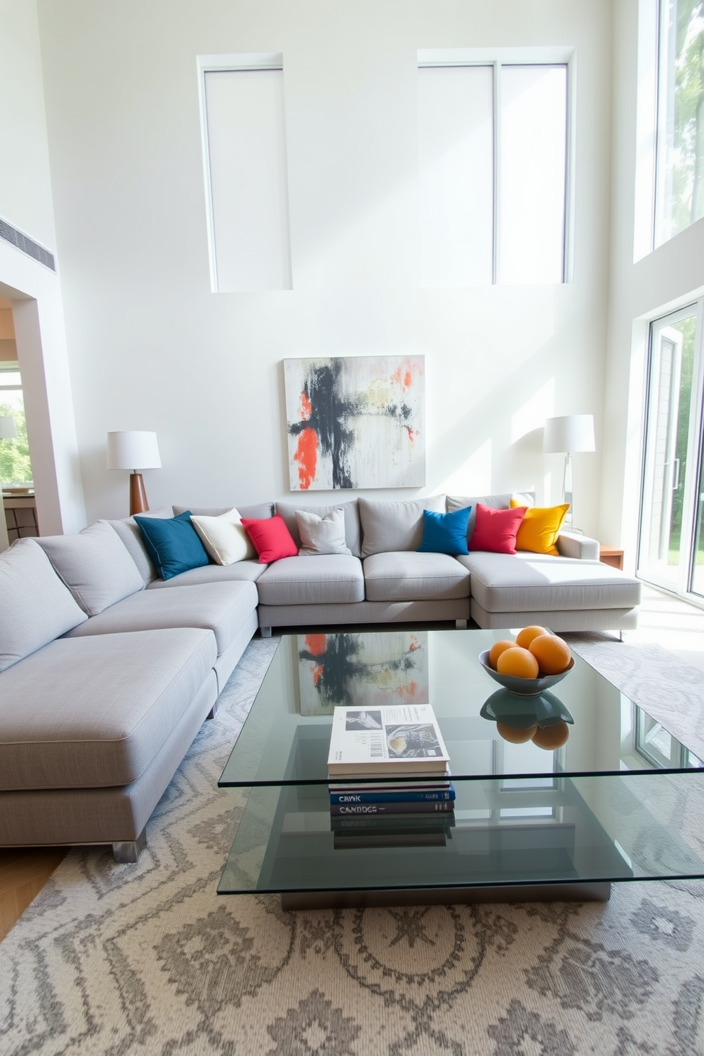 A modern living room featuring a glass coffee table that reflects light and enhances the sense of space. The seating area includes a plush sectional sofa in a soft gray fabric, complemented by colorful throw pillows for a vibrant touch. Large windows allow natural light to flood the room, creating an inviting atmosphere. The walls are painted in a crisp white, and a large piece of abstract art adds a focal point above the sofa.