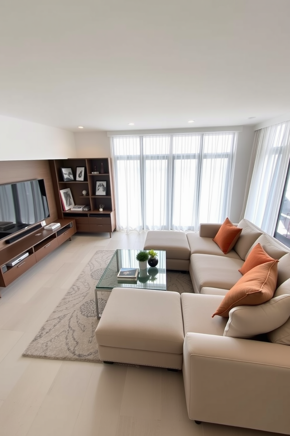 A contemporary family room featuring minimalist decor that emphasizes clean lines and open space. The focal point is a large sectional sofa in a neutral color, accented by bold throw pillows and a sleek coffee table made of glass and metal. A modern entertainment unit is mounted on the wall, showcasing a large flat-screen TV and decorative shelving with curated art pieces. Natural light floods the room through expansive windows, complemented by sheer curtains that add a touch of elegance.