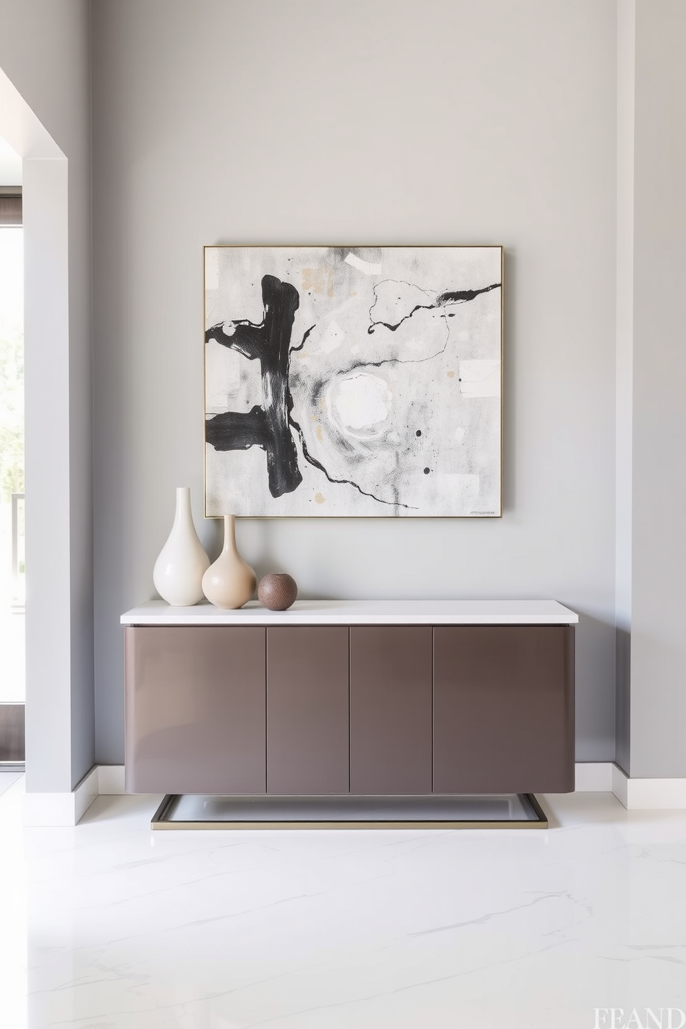 A contemporary foyer design featuring a sleek console table against a light gray wall. On the table, a collection of decorative vases in varying heights and shapes adds flair and interest to the space. The flooring is a polished white marble that complements the modern aesthetic. A large abstract painting hangs above the console, creating a striking focal point in the entryway.