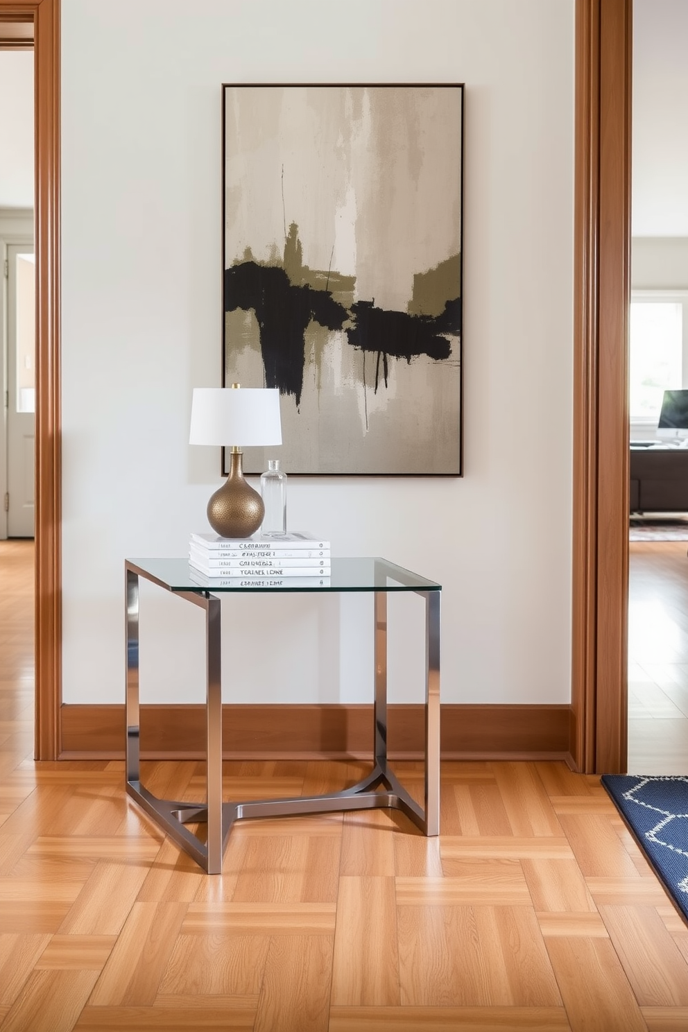 A contemporary foyer features a sleek console table made of glass and metal. Stylish hooks for coats and bags are mounted on a wall adorned with textured wallpaper in soft neutral tones. The flooring is a combination of polished wood and a chic area rug that adds warmth. A statement light fixture hangs from the ceiling, casting a welcoming glow over the space.