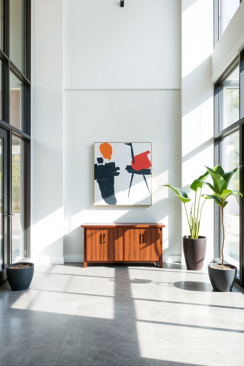 A contemporary foyer featuring bold artwork as the focal point. The space is illuminated by natural light streaming through large windows, highlighting a striking piece of abstract art on the main wall. The flooring is a sleek polished concrete, complemented by a minimalist console table in a rich wood finish. Flanking the entrance are two tall potted plants, adding a touch of greenery to the modern aesthetic.