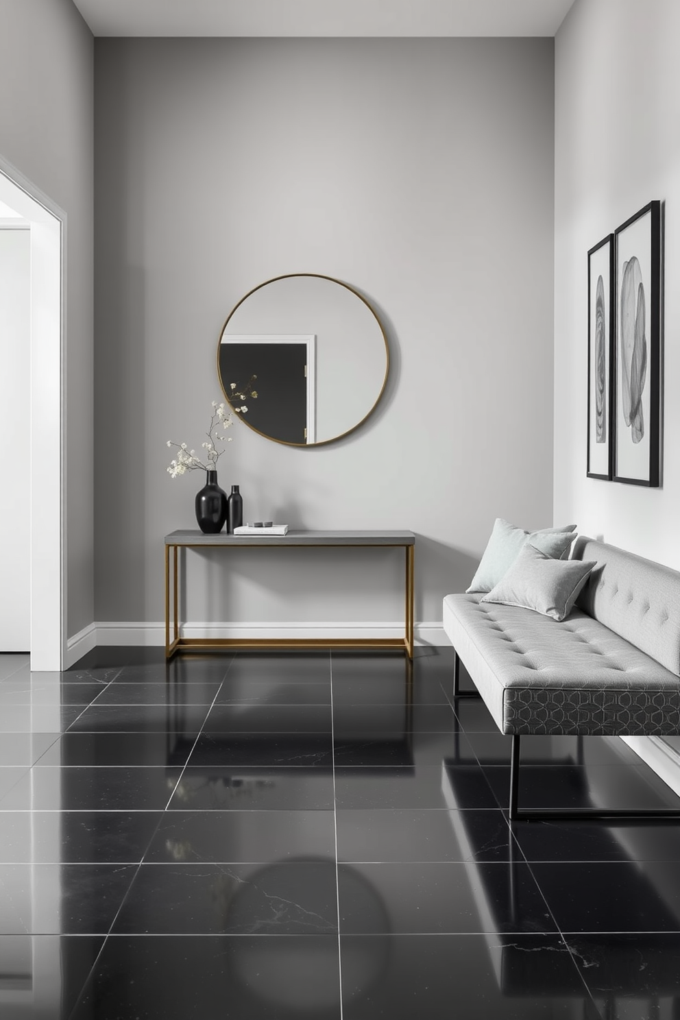 A contemporary foyer featuring a monochromatic color scheme that exudes elegance. The walls are painted in a soft gray tone, complemented by a sleek console table and a large round mirror above it. The flooring consists of polished black tiles, enhancing the sophisticated ambiance. A minimalist bench in a matching gray fabric is placed against one wall, adorned with a few decorative pillows for added comfort.