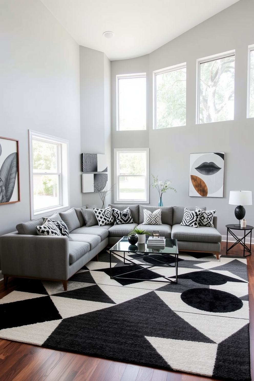 A contemporary living room featuring geometric patterns in the area rug and decorative pillows. The walls are painted in a soft gray, and a sleek sectional sofa is positioned around a glass coffee table. The rug showcases bold triangles and circles in a monochromatic color scheme, adding visual interest to the space. Large windows allow natural light to flood in, highlighting the modern artwork displayed on the walls.