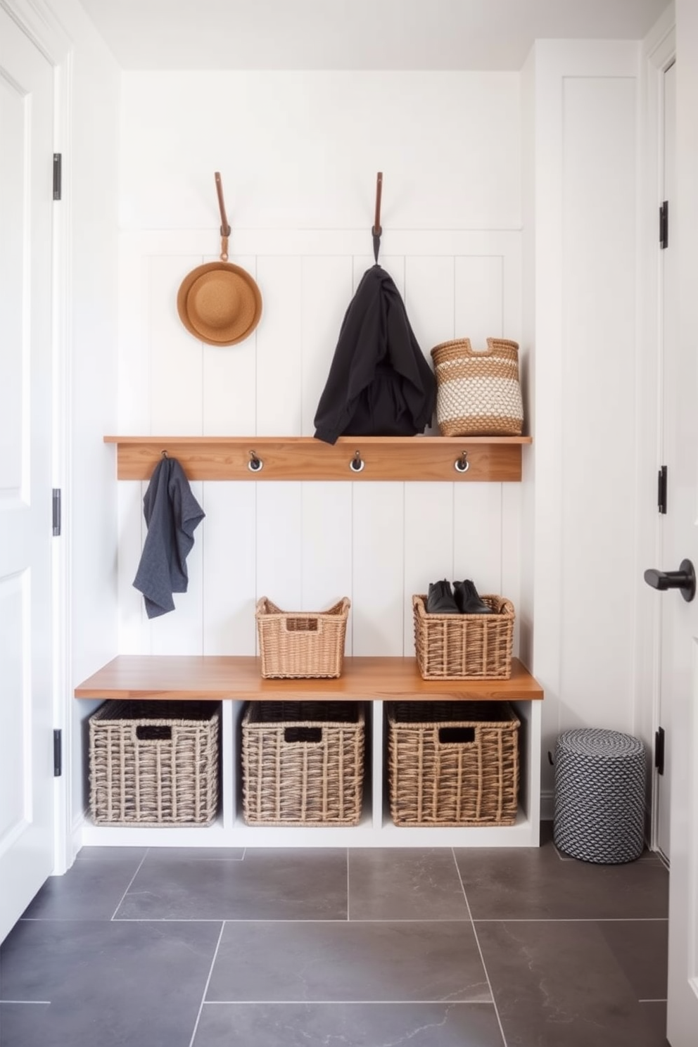 A contemporary mudroom features stylish baskets for shoe storage, neatly arranged on a wooden shelf. The walls are painted in a crisp white, while the floor is covered with a durable gray tile that complements the overall design.