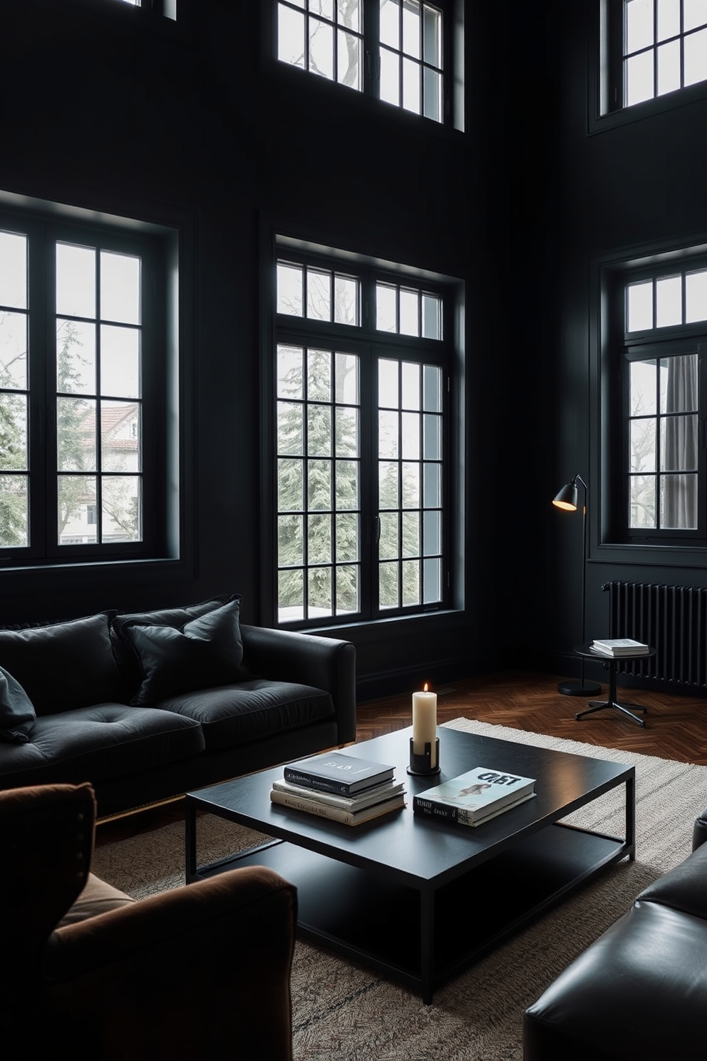 A dark and moody living room with black-framed windows that allow natural light to filter in. The walls are painted a deep charcoal gray, and the furniture features rich textures like velvet and leather. A sleek black coffee table sits in the center of the room, adorned with a few carefully curated books and a decorative candle. Soft ambient lighting from stylish floor lamps creates an inviting atmosphere, enhancing the overall elegance of the space.