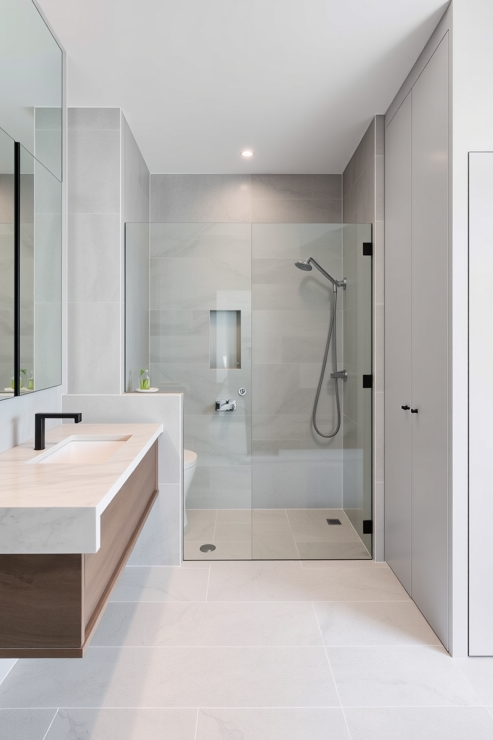 A sleek and modern bathroom design featuring a floating vanity with a seamless quartz countertop. The space is adorned with large format tiles in a soft gray tone, creating a clean and uncluttered look. The shower area showcases a frameless glass enclosure with a rainfall showerhead and minimalistic fixtures. Strategically placed storage solutions ensure easy access to essentials while keeping surfaces clear and tidy.