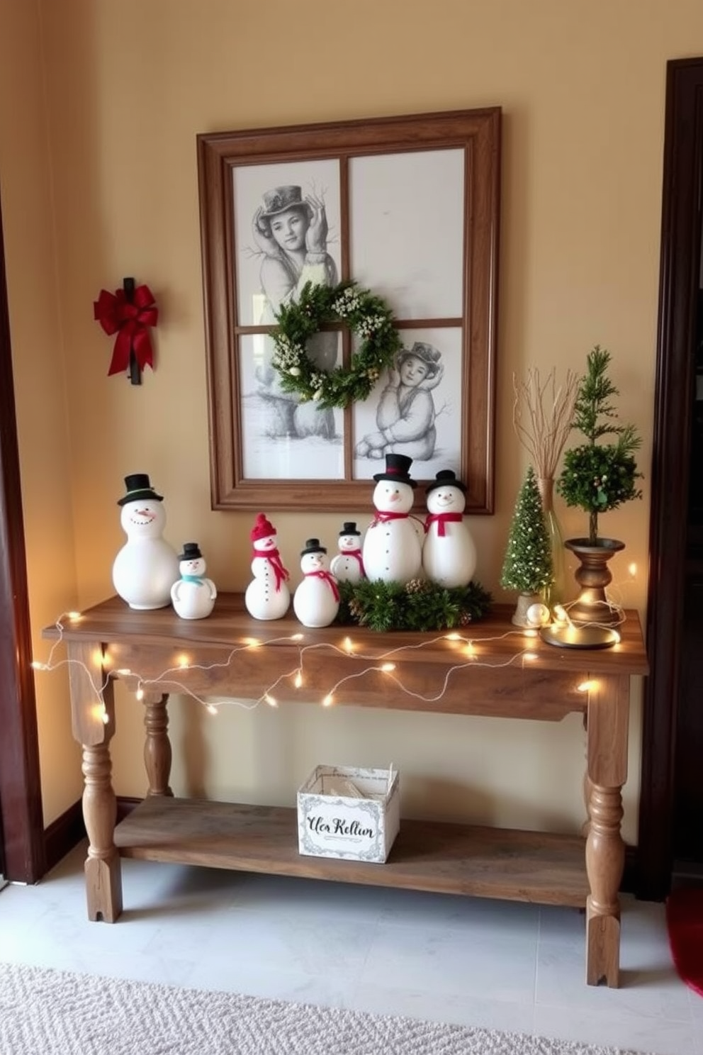 A charming entryway adorned for the holidays features a rustic wooden entry table. On the table, several snowman figurines of varying sizes bring a playful and festive touch to the decor. The walls are painted in a warm beige tone, creating a cozy atmosphere. A string of twinkling fairy lights is draped along the table's edge, enhancing the holiday spirit.