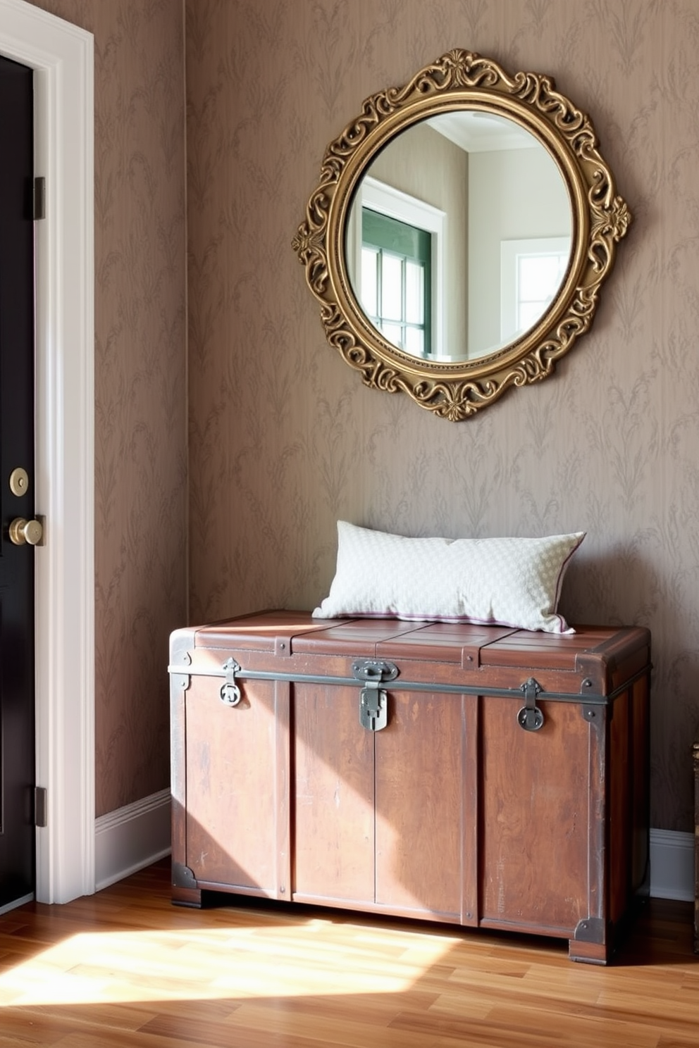 A vintage trunk serves as a unique storage solution in the entryway, adding character and charm to the space. It is positioned against a wall adorned with a muted wallpaper, providing a stylish contrast to the trunk's weathered wood finish. Next to the trunk, a small bench with a plush cushion invites guests to sit while removing their shoes. Above the trunk, a round mirror with an ornate frame reflects natural light, enhancing the welcoming atmosphere of the entryway.