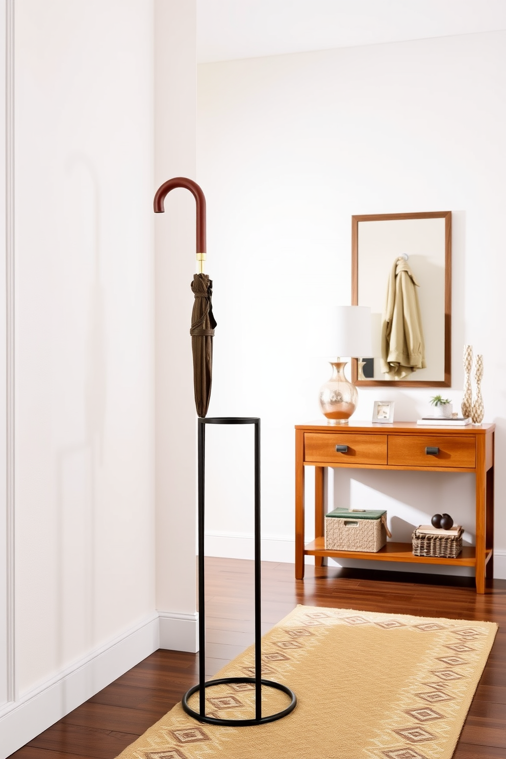 A stylish umbrella stand made of sleek metal with a minimalist design sits in the corner of a bright entryway. Surrounding the stand are decorative elements like a small potted plant and a modern coat rack, enhancing the functional yet aesthetic appeal of the space. The entryway features a warm wood console table against the wall, adorned with a chic lamp and a framed mirror above it. Soft, neutral tones on the walls create a welcoming atmosphere, while a patterned runner rug adds a touch of personality underfoot.