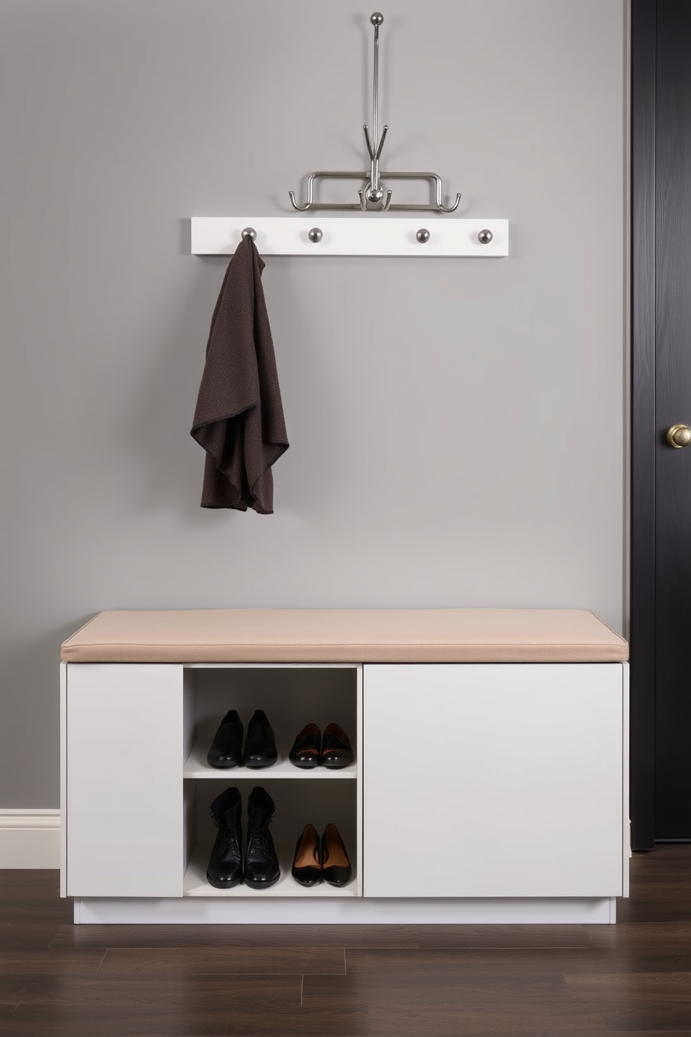 A sleek shoe storage unit is integrated seamlessly under a modern bench in the entryway. The bench features a plush cushion in a neutral tone, providing comfort while putting on shoes. The shoe storage is designed with clean lines and a minimalist aesthetic, showcasing a mix of open and closed compartments. A stylish coat rack is mounted on the wall above, complementing the overall design with a touch of elegance.