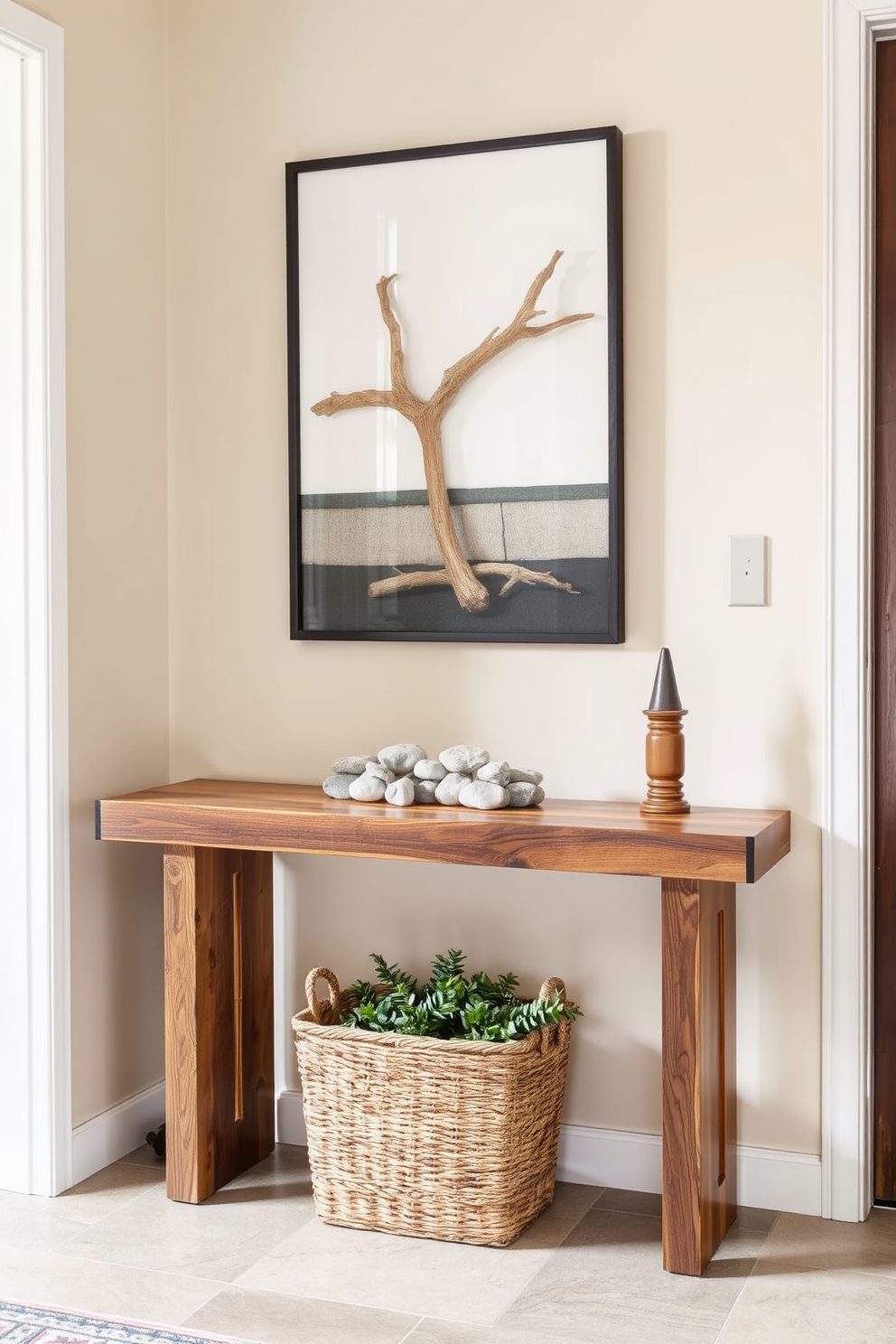 A stylish entryway featuring a sleek table made of reclaimed wood. The table is adorned with a collection of smooth river stones and a piece of driftwood art, creating a harmonious blend of natural elements. The walls are painted in a soft beige, complementing the earthy tones of the table. A woven basket filled with greenery sits beneath the table, adding warmth and texture to the space.