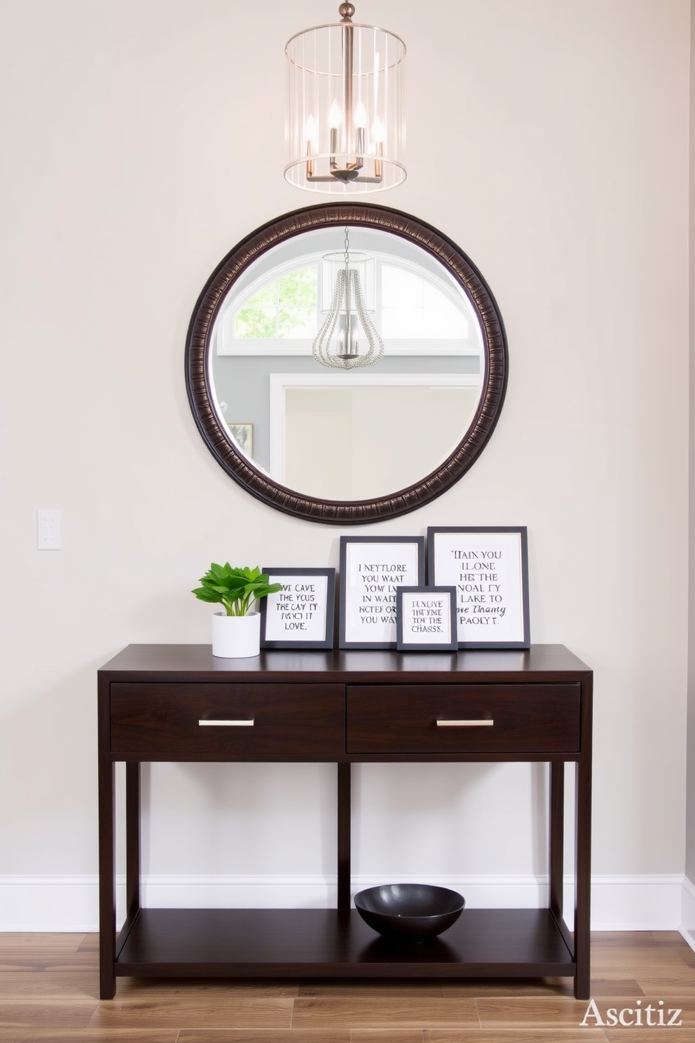 A stylish entryway featuring a sleek console table made of dark wood. Above the table, a large round mirror with a decorative frame reflects the light from an elegant chandelier. On the table, a collection of framed inspirational quotes in varying sizes adds a personal touch. A small potted plant and a decorative bowl for keys complete the look, creating an inviting and organized space.