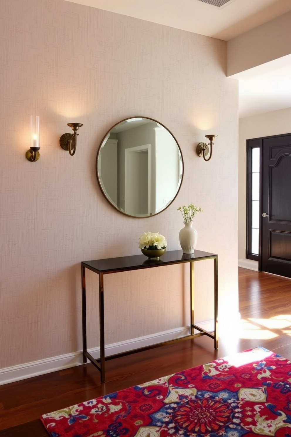 A sophisticated entryway featuring sconce lighting that casts a warm glow across the space. The walls are adorned with a textured wallpaper in a soft neutral tone, complemented by a slim console table beneath a large round mirror. On either side of the console, elegant sconces with intricate designs provide both functionality and style. The flooring is a rich hardwood that adds warmth, while a vibrant area rug brings a pop of color and texture to the entryway.