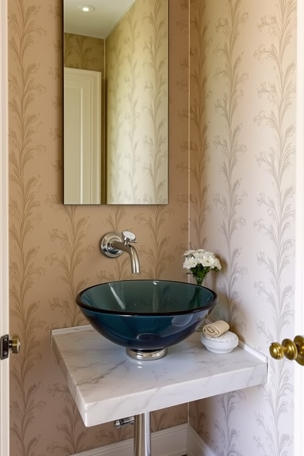 A unique vessel sink made of hand-blown glass serves as the stunning focal point of this elegant European powder room. The walls are adorned with intricate wallpaper featuring a delicate floral pattern, creating a warm and inviting atmosphere. A sleek wall-mounted faucet complements the vessel sink, while a small marble countertop provides space for decorative items. Soft, ambient lighting illuminates the room, highlighting the rich textures and colors of the design.