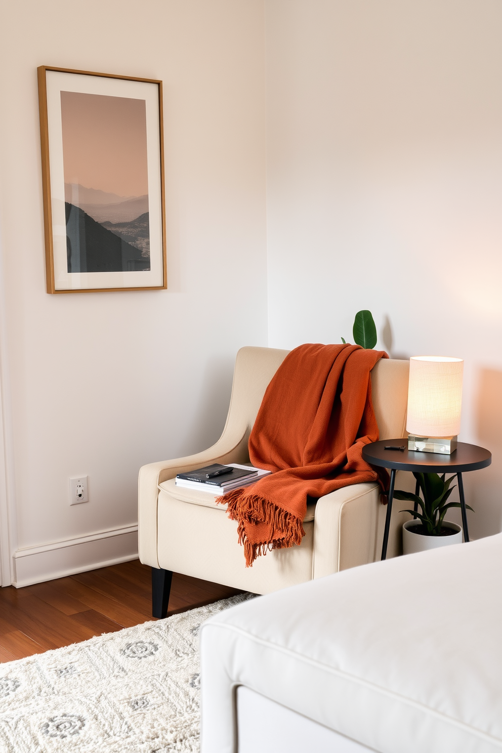 A cozy corner in a stylish apartment features a plush armchair upholstered in soft fabric, positioned next to a small round side table. A warm throw blanket is draped over the chair, and a stack of books rests on the table, accompanied by a decorative lamp that casts a soft glow. The walls are adorned with subtle artwork that complements the neutral color palette, creating an inviting atmosphere. A potted plant sits nearby, adding a touch of greenery to the space, while a soft rug anchors the area, enhancing the overall comfort of the corner.