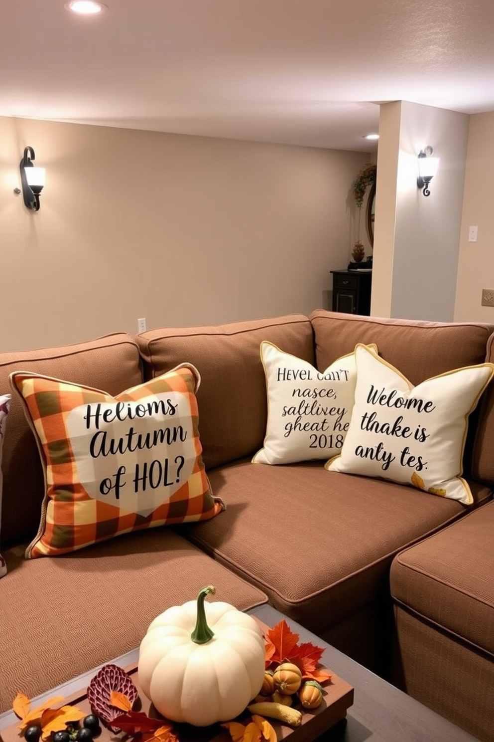 Seasonal throw pillows featuring inspirational quotes are arranged on a cozy sectional sofa in a warmly lit basement. The pillows showcase autumn colors and patterns, creating a welcoming atmosphere for relaxation and gatherings. Decorative elements such as small pumpkins and autumn leaves are strategically placed around the space to enhance the fall theme. Soft, ambient lighting from wall sconces complements the inviting decor, making the basement a perfect retreat for the season.