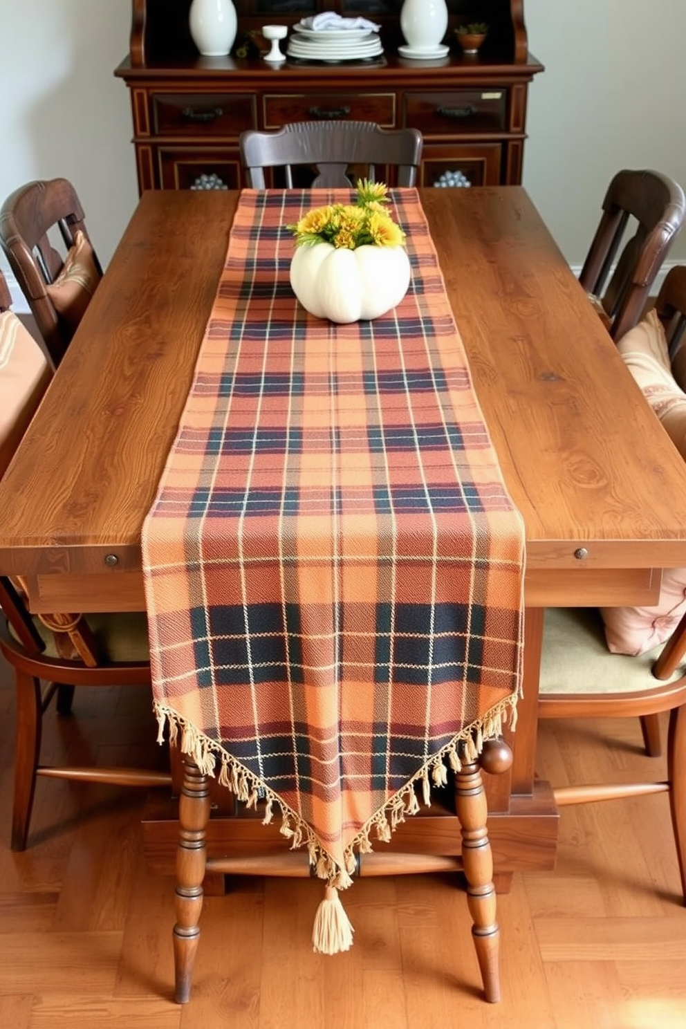 A warm plaid tablecloth drapes over a rustic wooden dining table, creating an inviting atmosphere for autumn gatherings. Surrounding the table, upholstered chairs in earthy tones complement the seasonal decor with centerpieces of pumpkins and candles.