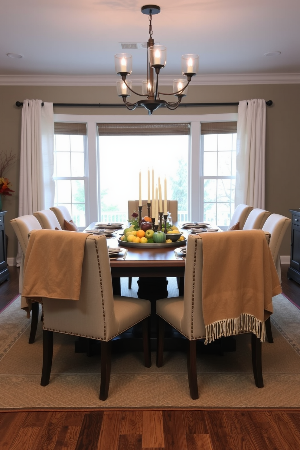 A cozy dining room setting featuring a large wooden table surrounded by upholstered chairs. Warm throw blankets are casually draped over the backs of the chairs, inviting guests to relax and enjoy the meal. The table is adorned with a simple yet elegant centerpiece of seasonal fruits and candles. Soft, ambient lighting enhances the inviting atmosphere, creating a perfect space for fall gatherings.