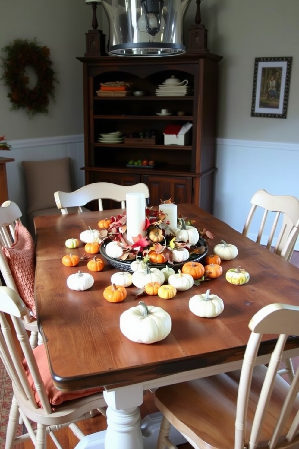 A cozy fall dining room setting featuring a rustic wooden table adorned with miniature pumpkins in various sizes and colors scattered across its surface. Surrounding the table are mismatched chairs with warm, inviting cushions, and a centerpiece of autumn leaves and candles adds to the seasonal charm.