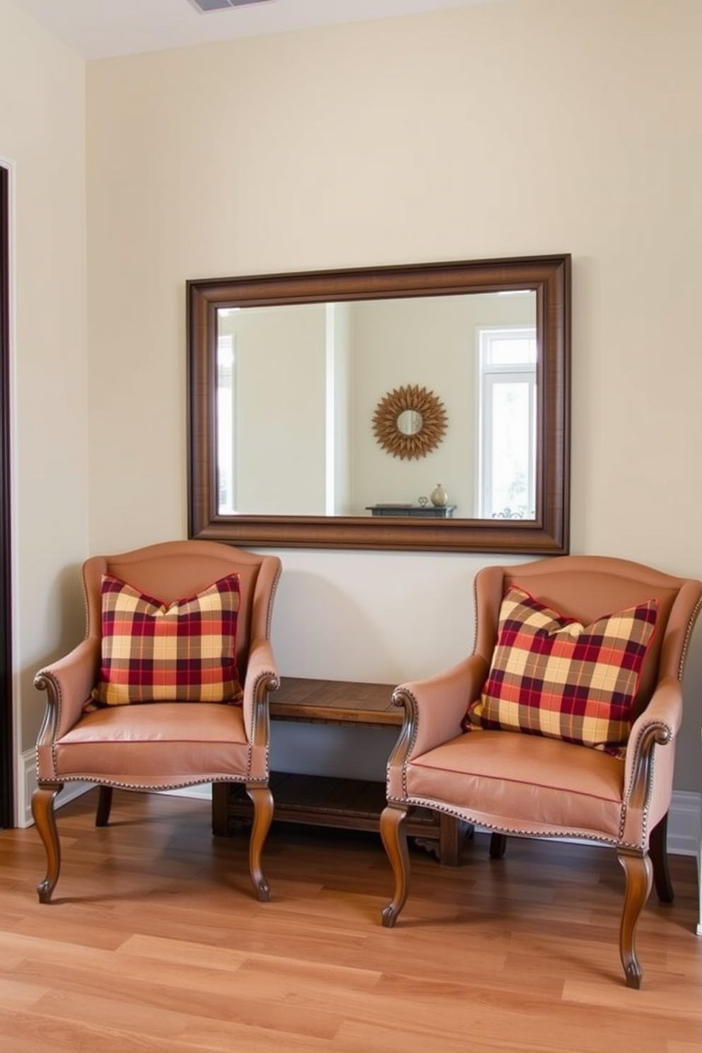 A cozy entryway featuring two elegant chairs adorned with plaid pillows in warm autumn colors. The walls are painted a soft beige, and a rustic wooden bench sits beneath a large mirror, reflecting the inviting atmosphere.