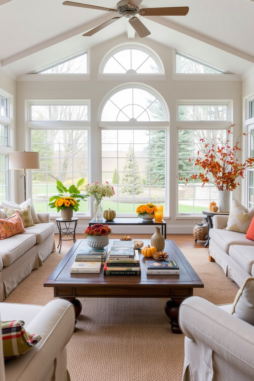 A cozy sunroom filled with natural light. A large coffee table is adorned with seasonal books featuring autumn themes, surrounded by comfortable seating and vibrant fall decor.