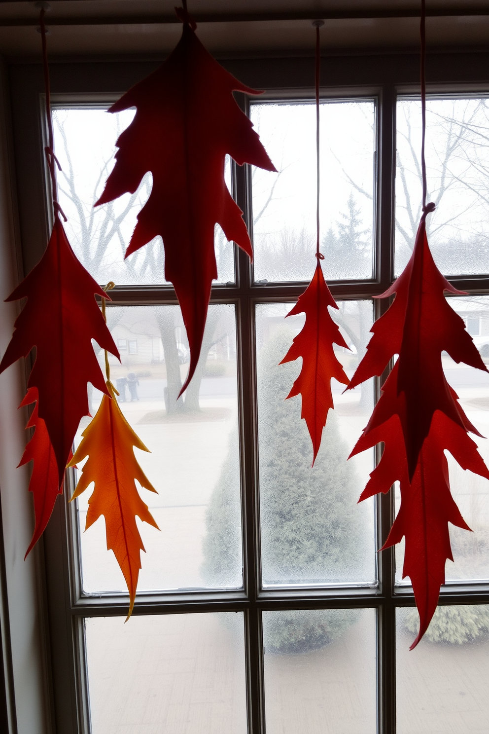 A cozy window display featuring hanging felt leaves gracefully draped from the window frame. The leaves are in various autumn colors, creating a warm and inviting atmosphere for fall.