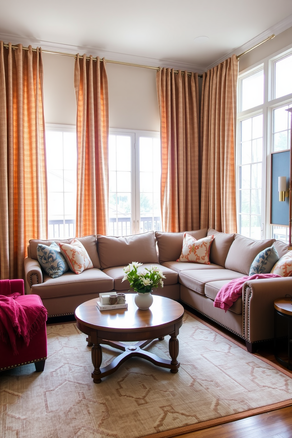 A cozy family room featuring a large sectional sofa adorned with textured throw blankets in various shades of gray and cream. The walls are painted a soft taupe, and a plush area rug anchors the seating arrangement, creating an inviting atmosphere. Natural light floods the space through oversized windows, showcasing a view of the lush garden outside. A wooden coffee table sits in the center, topped with a stack of art books and a decorative bowl, adding a touch of elegance to the room.