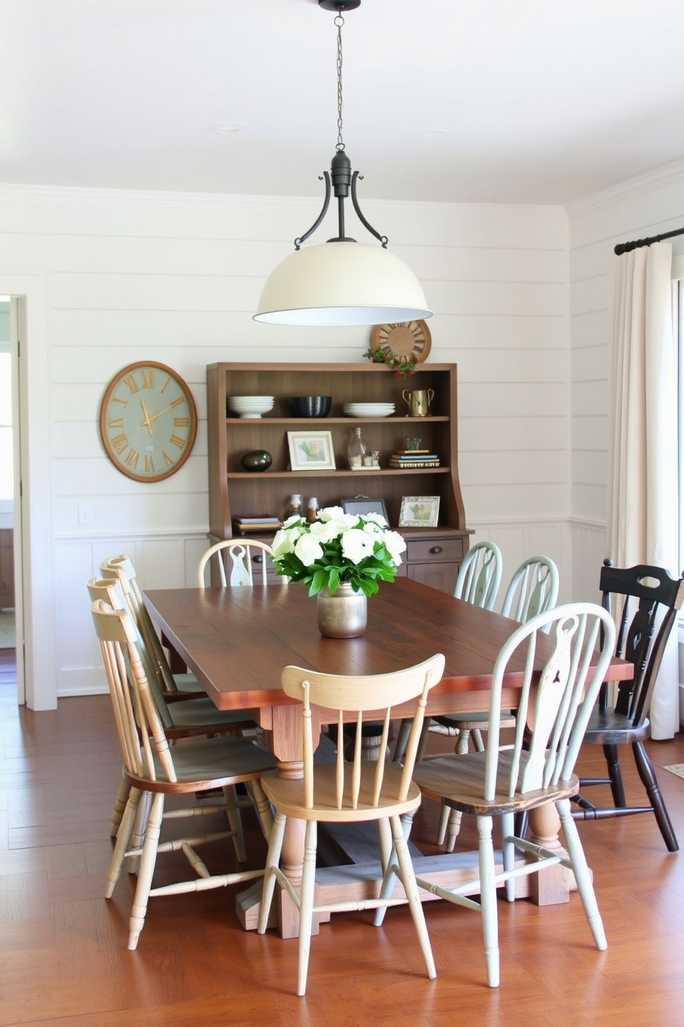 A charming farmhouse table made of reclaimed wood sits in the center of a cozy dining room. Surrounding the table are mismatched chairs in various colors and styles, adding a playful touch to the rustic decor. Above the table, a vintage chandelier hangs, casting a warm glow over the space. The walls are adorned with shiplap, and a large window lets in natural light, enhancing the inviting atmosphere.