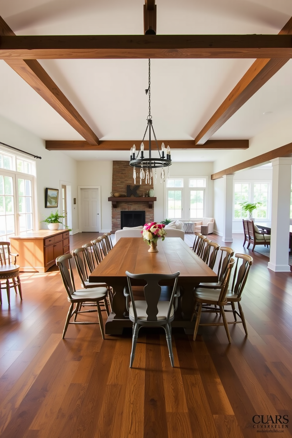 Open floor plan design featuring a spacious farmhouse dining room with a large wooden table surrounded by mismatched chairs. The room is illuminated by a rustic chandelier hanging from a beamed ceiling, and large windows allow natural light to fill the space.