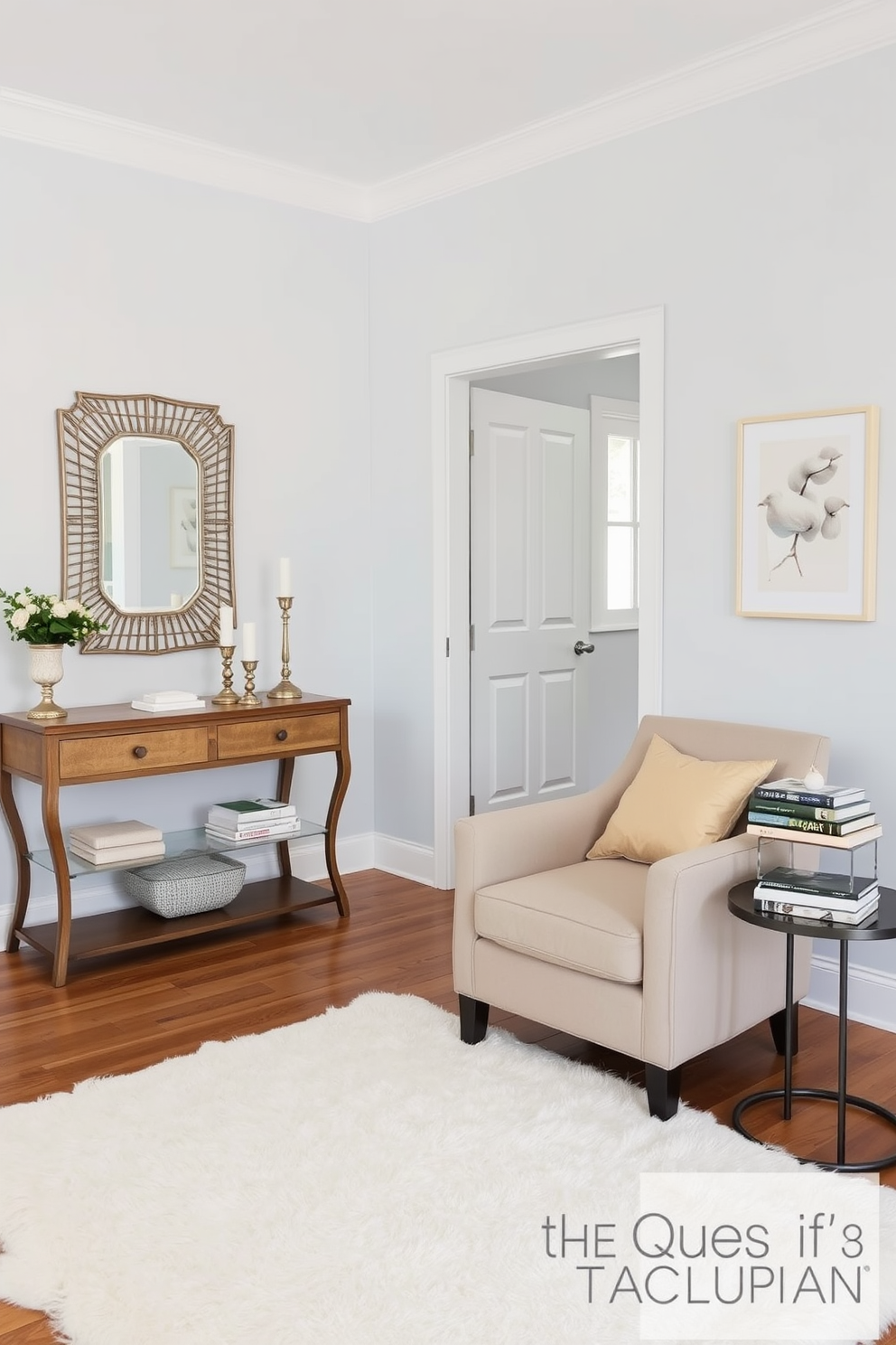 A serene foyer space that welcomes guests with its soft color palette. The walls are painted in a gentle light blue, complemented by a plush white area rug on the wooden floor. A stylish console table sits against one wall, adorned with a decorative mirror and a few carefully placed candles. To the side, a comfortable armchair in a muted beige invites relaxation, with a small side table holding a stack of art books.