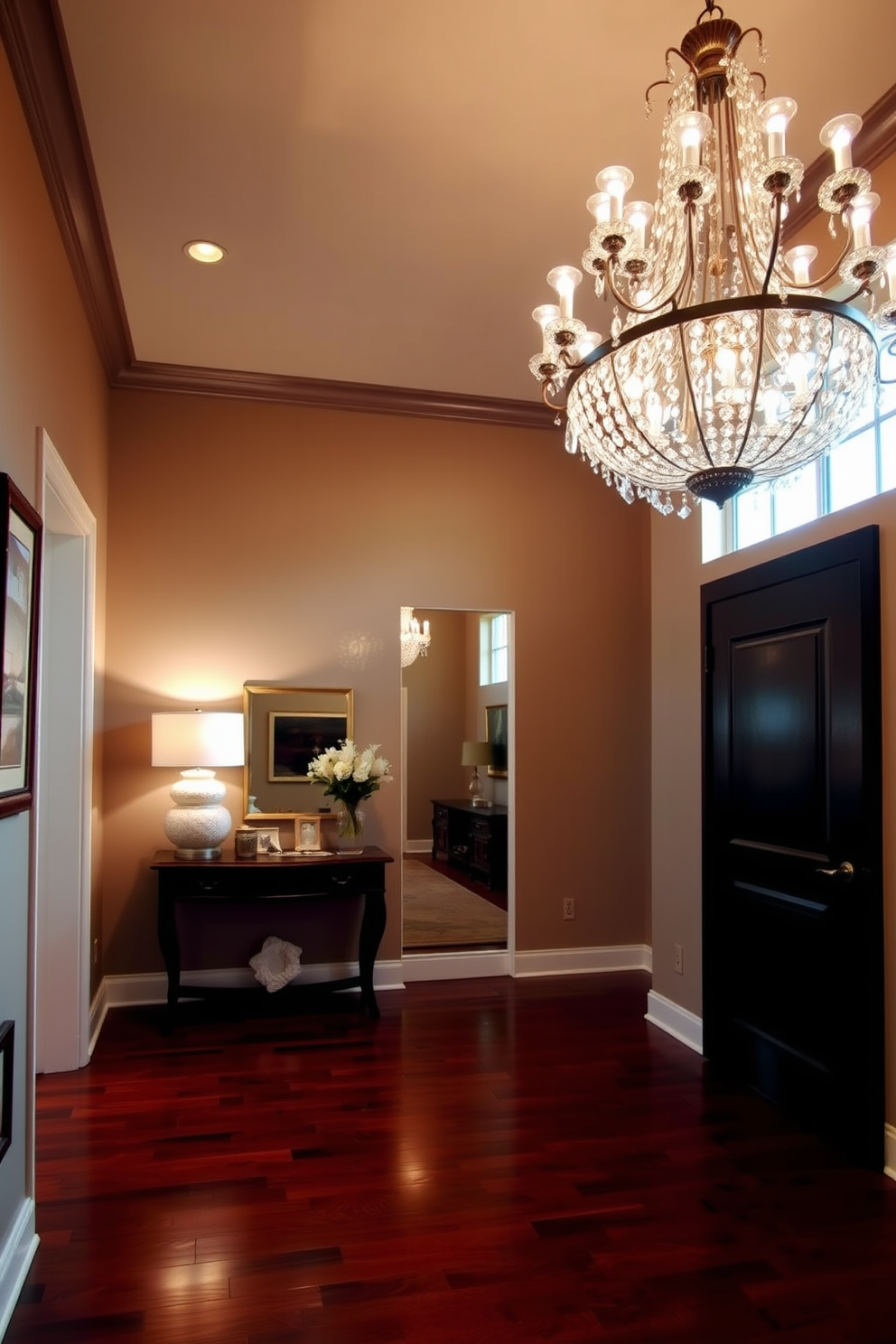 A stunning foyer design with an elegant chandelier hanging from the ceiling, casting a warm glow throughout the space. The walls are adorned with tasteful artwork and a console table sits against one side, topped with decorative items and a stylish lamp. The flooring features rich hardwood that complements the overall color palette, creating a welcoming atmosphere. A large mirror is positioned across from the entrance, enhancing the sense of space and reflecting the beautiful lighting fixtures.