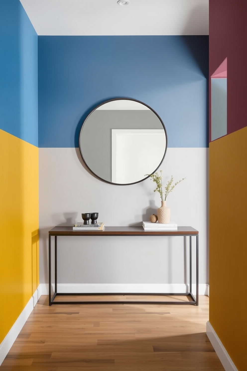 A striking foyer with a bold color-blocking design. The walls are divided into three sections, featuring a vibrant blue, a soft gray, and a warm mustard yellow, creating a contemporary and inviting atmosphere. A sleek console table in a dark wood finish sits against the wall, adorned with a few carefully selected decorative items. Above the table, an oversized round mirror reflects the dynamic colors, enhancing the modern aesthetic of the space.