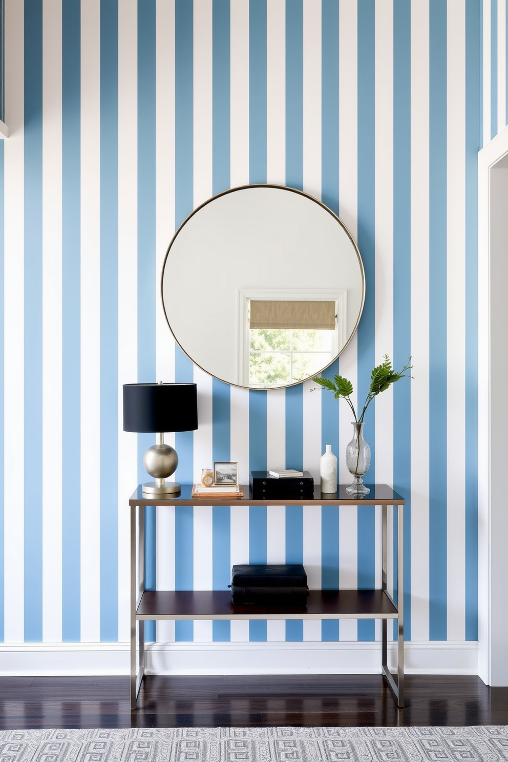 A foyer with painted stripes in varying shades of blue and white creates a fresh and inviting atmosphere. The stripes run vertically, adding height to the space and drawing the eye upward. A sleek console table sits against the striped wall, adorned with a stylish lamp and a few decorative items. A large round mirror above the table reflects light and enhances the sense of openness in the foyer.