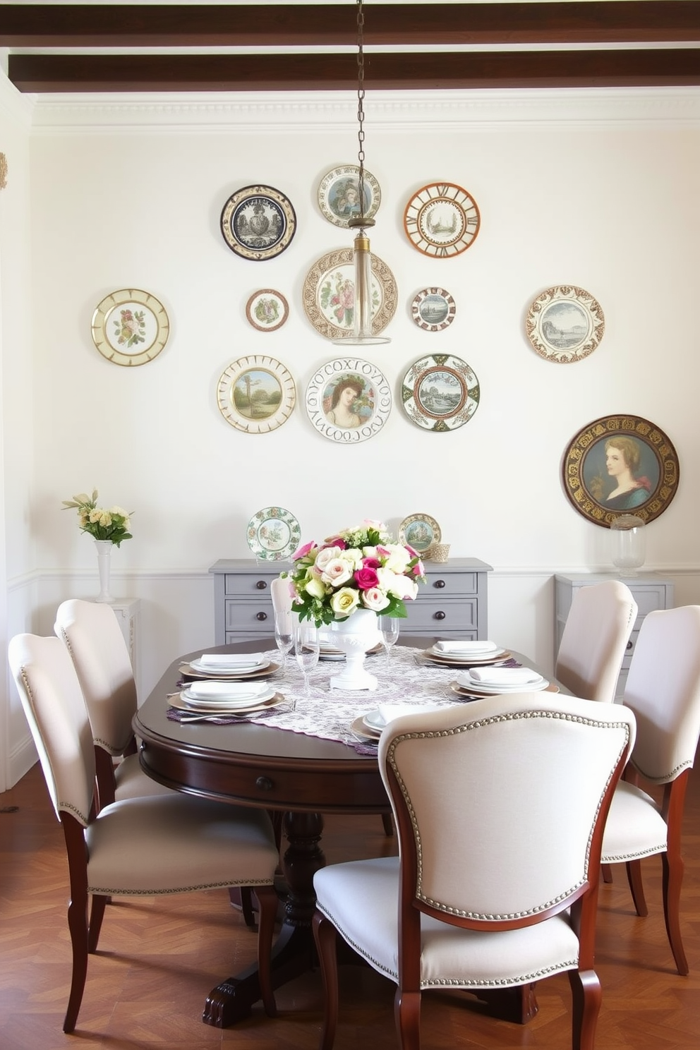 A charming French dining room featuring decorative plates as wall accents. The plates are arranged in an artistic pattern on a soft white wall, complementing the elegant wooden dining table set for six. The table is adorned with a delicate lace tablecloth and a centerpiece of fresh flowers in a vintage vase. Surrounding the table are upholstered chairs in a light pastel fabric, adding warmth and sophistication to the space.