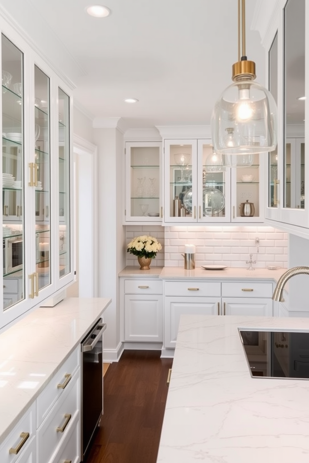 A modern galley kitchen featuring sleek glass-front cabinets that showcase elegant dishware and glassware. The countertops are made of polished quartz, and the space is illuminated by pendant lights hanging above the central island. The cabinetry is painted in a soft white hue, creating a bright and airy feel. A stylish backsplash of subway tiles adds a touch of sophistication to the overall design.