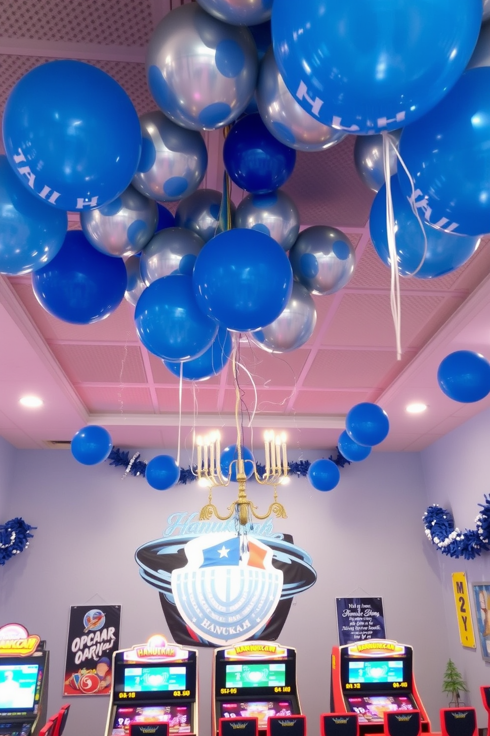 A vibrant game room decorated for Hanukkah features clusters of blue and silver balloons floating above the gaming area. The walls are adorned with festive garlands and string lights, creating a cheerful and inviting atmosphere.