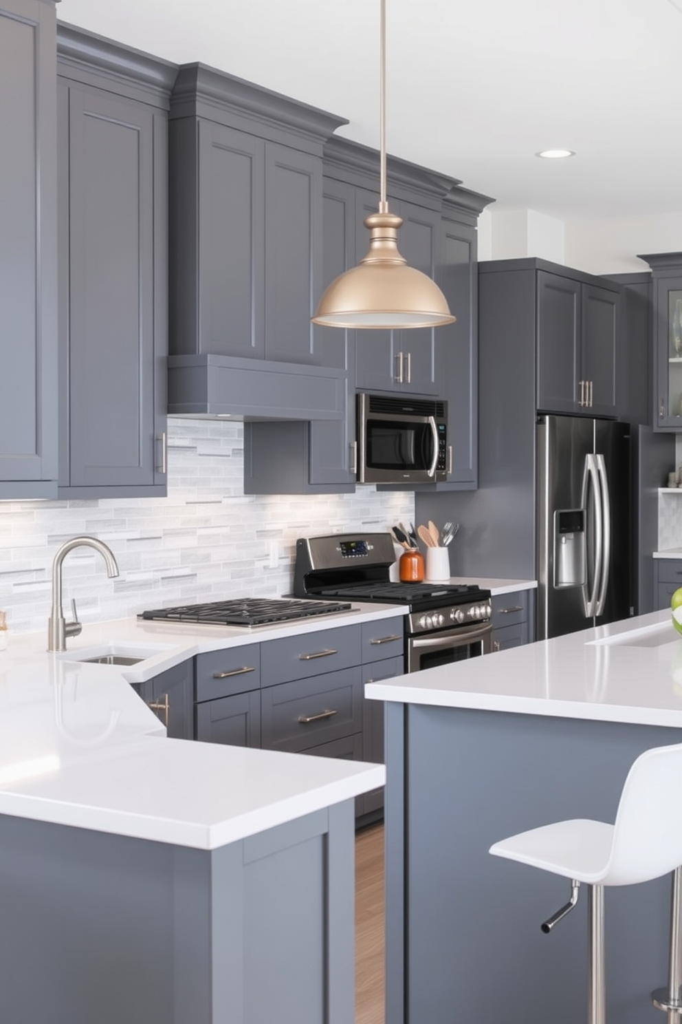 A modern kitchen featuring gray cabinetry with sleek white countertops. Stainless steel appliances are seamlessly integrated, and a large island with bar seating invites casual dining. The walls are adorned with subtle gray tiles that reflect light, enhancing the spacious feel. A stylish pendant light hangs above the island, providing both illumination and a focal point in the design.