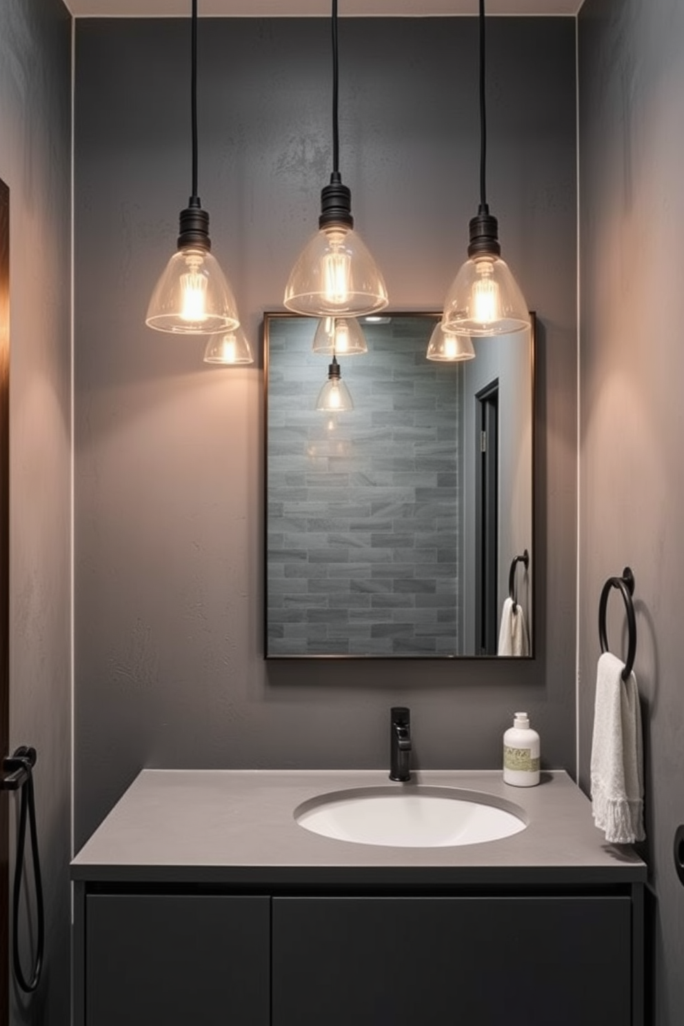 A modern bathroom featuring industrial gray fixtures and lighting. The walls are adorned with textured gray tiles, and a sleek gray vanity complements the overall aesthetic. The space is illuminated by pendant lights with an industrial design, casting a warm glow. A large mirror with a minimalist frame reflects the stylish elements of the room.