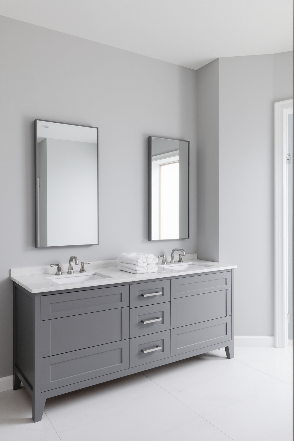 A serene bathroom space featuring subtle gray tones throughout. The walls are painted in a soft gray hue, complemented by a sleek gray vanity with a white quartz countertop. Large rectangular mirrors with minimalist frames are mounted above the vanity, reflecting the calming ambiance. The floor is adorned with light gray tiles, and plush white towels are neatly arranged on the vanity.