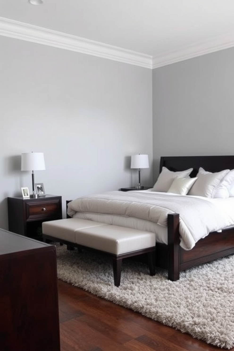 A serene gray bedroom featuring light gray walls that create a calming atmosphere. The room is furnished with dark wood furniture, including a sleek bed frame and matching nightstands, enhancing the contrast and elegance of the space. Soft bedding in shades of white and silver adds a touch of luxury, while decorative pillows provide a cozy accent. A plush area rug in neutral tones anchors the room, inviting comfort and warmth underfoot.