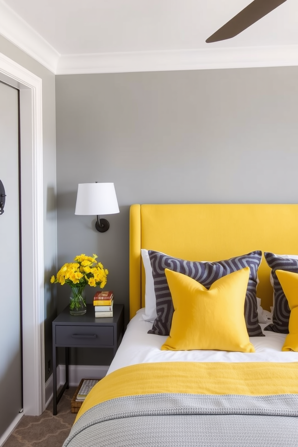 A stylish gray bedroom featuring bold yellow accents. The walls are painted in a soft gray tone, complemented by a yellow upholstered headboard and vibrant throw pillows on the bed.