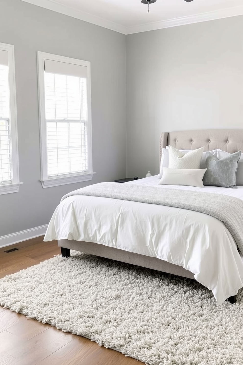 A serene gray bedroom featuring navy blue accents. The walls are painted in a soft gray, complemented by a plush navy blue upholstered headboard and matching bedding. Natural light filters through sheer white curtains, casting a gentle glow on the room. A stylish wooden nightstand holds a modern lamp, while a cozy reading nook with a navy blue armchair invites relaxation.