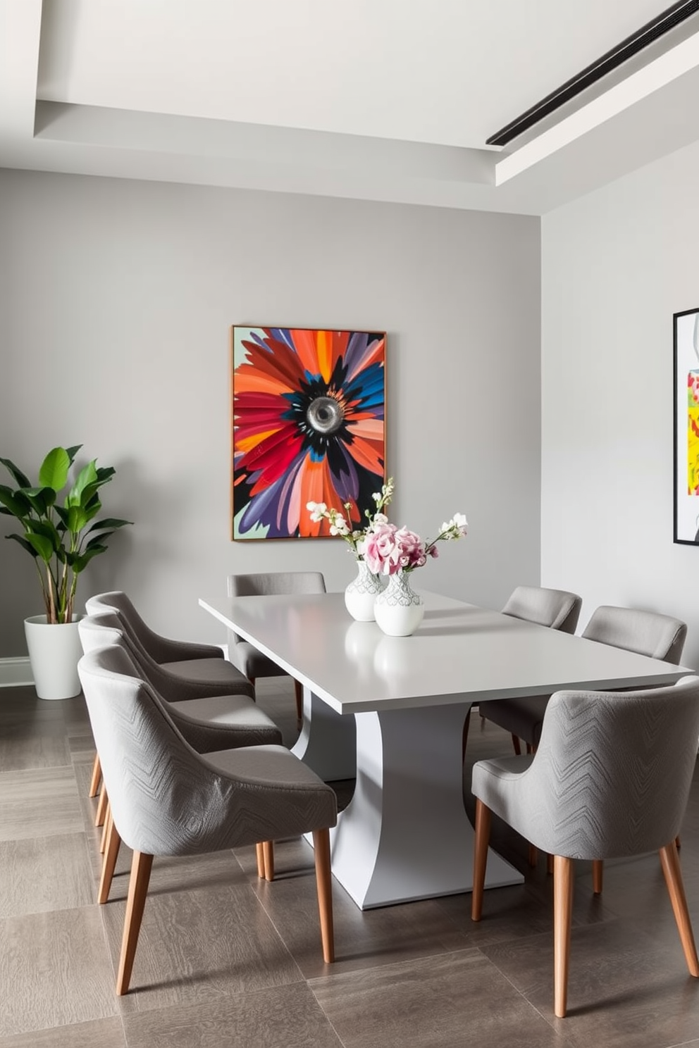 A stylish gray dining room featuring a mix of geometric and floral patterns in the textiles. The table is set with a white tablecloth adorned with gray stripes, while the chairs are upholstered in a bold floral fabric that complements the overall theme. The walls are painted in a soft gray tone, enhancing the cozy atmosphere of the space. A statement light fixture hangs above the table, adding a touch of elegance to the design.