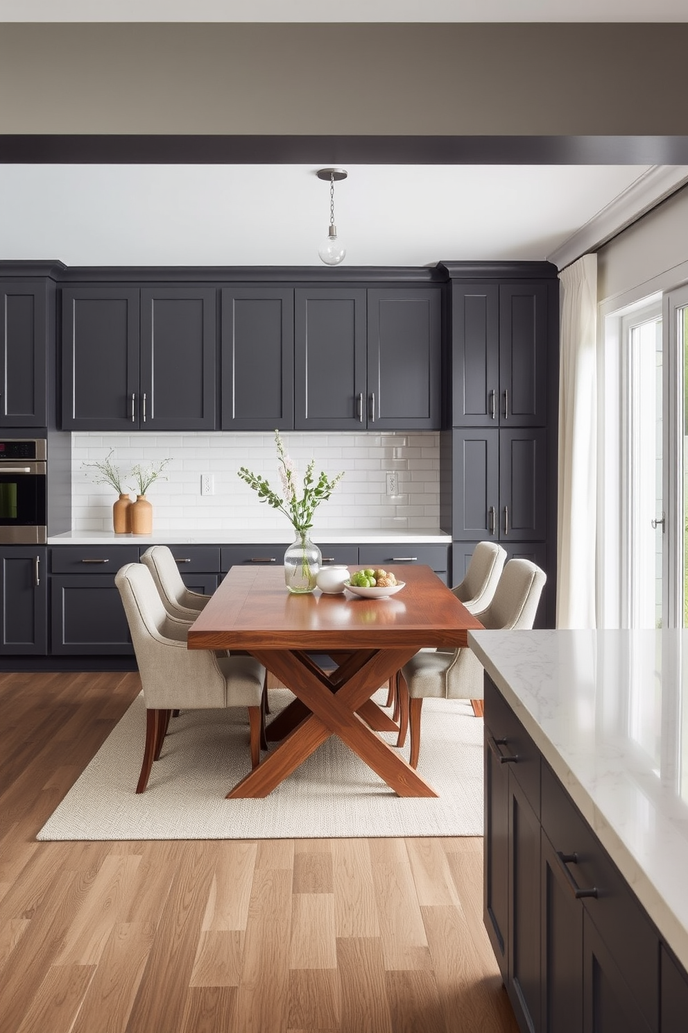 A contemporary dining room featuring dark gray cabinetry that complements light-colored countertops. The space is enhanced by a large wooden dining table surrounded by stylish upholstered chairs, creating an inviting atmosphere.