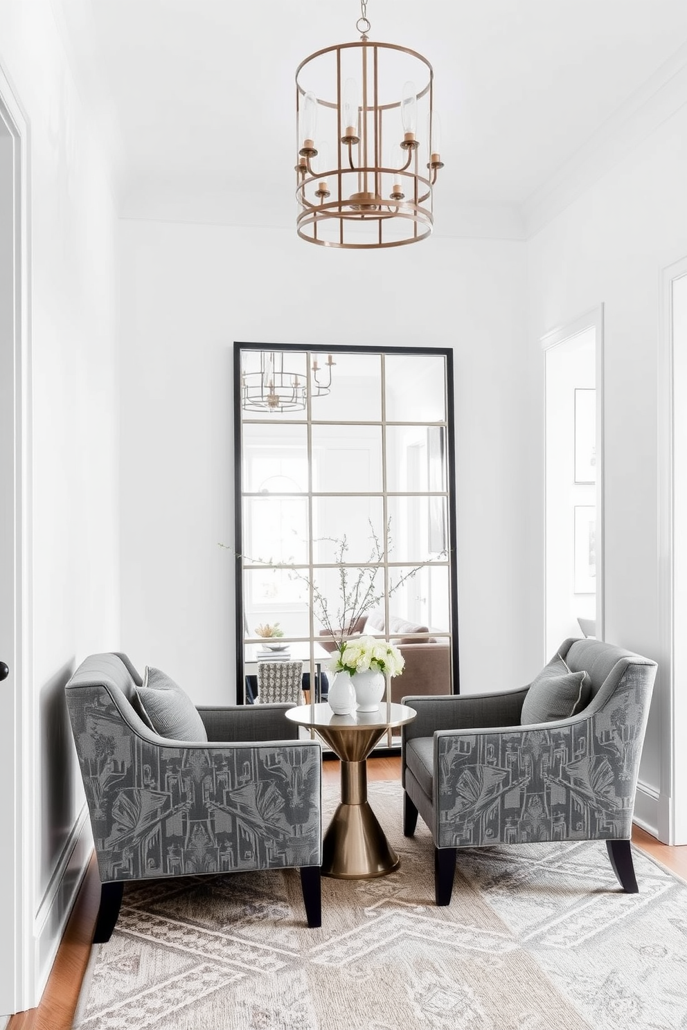 A stylish foyer featuring gray accent chairs that invite comfort and relaxation. The space is adorned with a statement light fixture and a large mirror that enhances the room's brightness. The walls are painted in a soft white hue, creating a clean backdrop for the gray chairs. A patterned area rug adds warmth and texture to the entryway, making it feel welcoming and sophisticated.