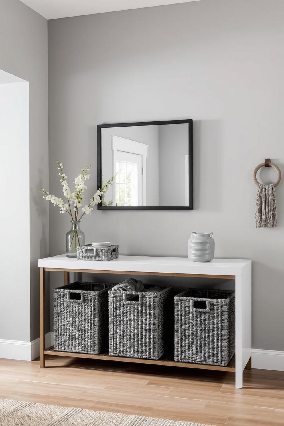 A contemporary gray side table is positioned against a light-colored wall, adorned with a stack of stylish books and a small decorative plant. The flooring features a sleek dark wood finish, complementing the modern aesthetic of the space. In the foyer, a gray color palette is utilized with a minimalist console table and a large round mirror above it. The walls are accented with subtle artwork, creating an inviting atmosphere that welcomes guests.