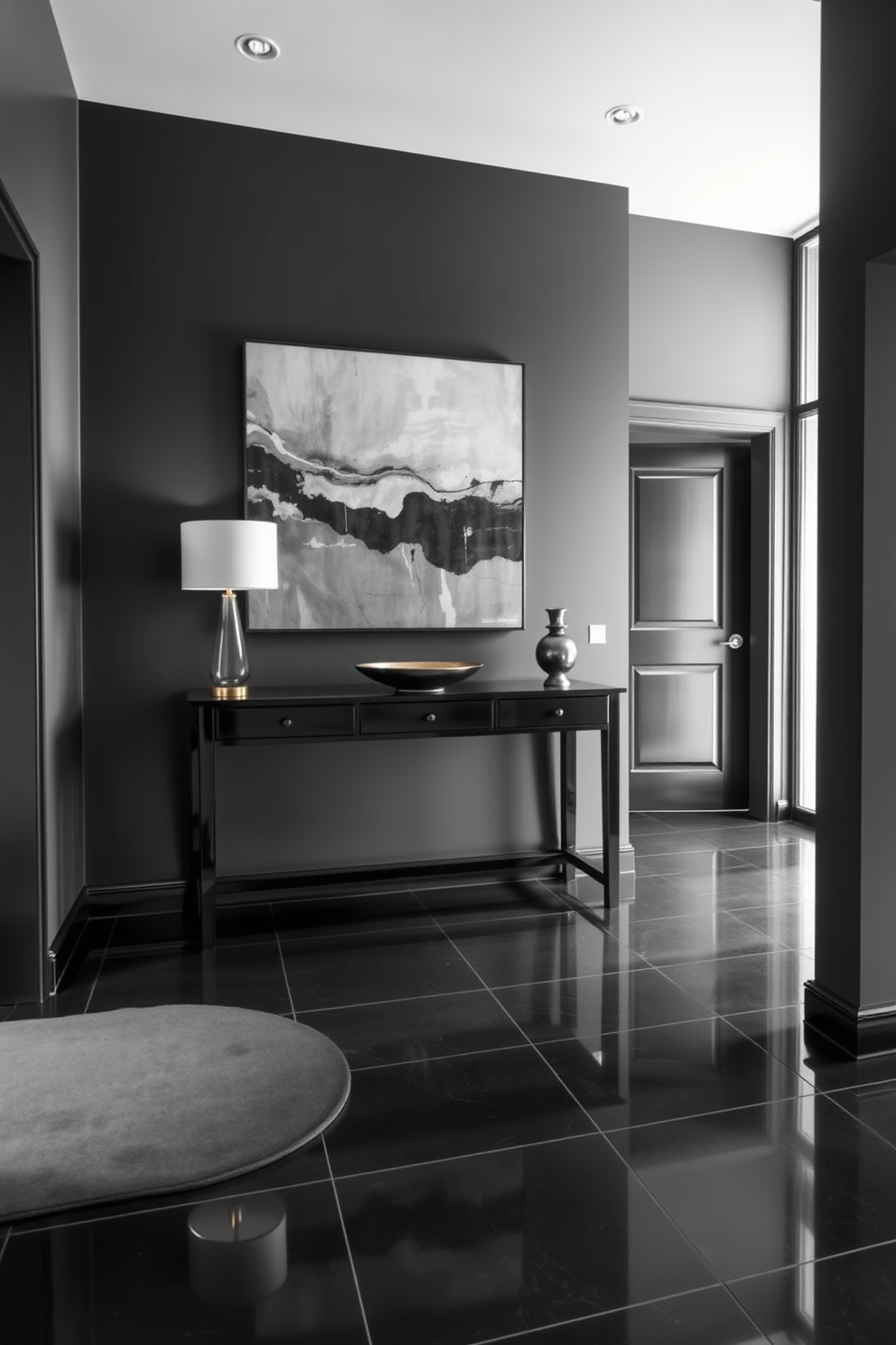 A stunning foyer featuring a dramatic gray and black color contrast. The walls are painted in a deep charcoal gray, while the floor showcases sleek black tiles that reflect light beautifully. An elegant console table made of black wood stands against the wall, adorned with a minimalist lamp and a decorative bowl. A large abstract artwork in shades of gray and black hangs above the table, creating a striking focal point in the space.