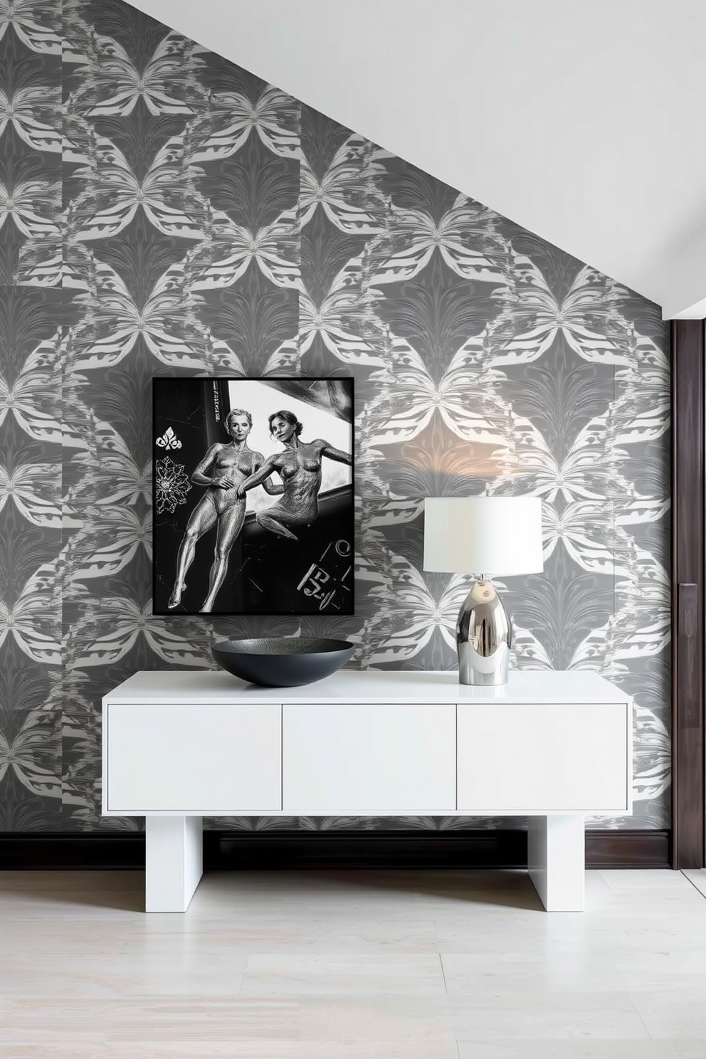 A stunning foyer adorned with gray and white patterned wallpaper that creates a striking visual impact. The space features a sleek console table with a minimalist design, topped with a decorative bowl and a stylish lamp.