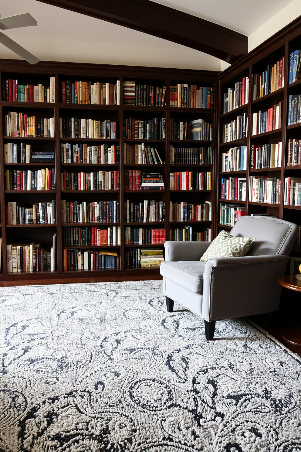 A cozy home library featuring a plush gray rug that adds warmth and comfort to the space. The walls are lined with dark wooden bookshelves filled with an array of books, while a comfortable reading chair is positioned near a large window, allowing natural light to flood in.